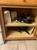 Contents of cabinet on the right side of stove pots and pans