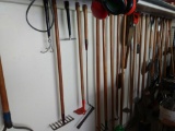 Yard tool lot including shovels, rakes, and more hanging on back wall of the garage