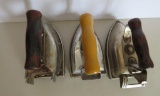 Three vintage electric irons and trivets