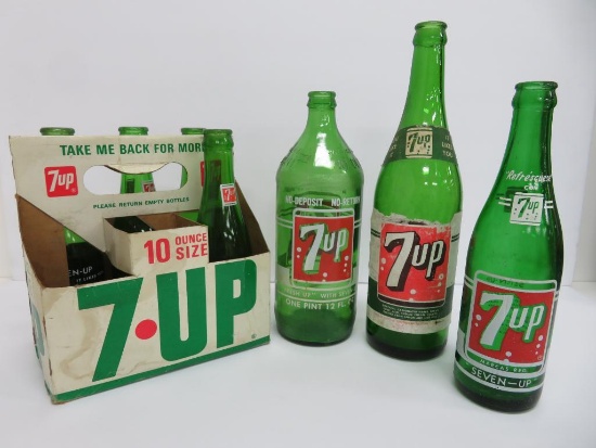 Seven assorted types and sizes of vintage 7 up bottles and paper carrier