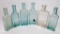Six clear and aqua medicine bottles