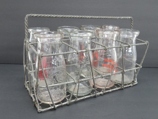 Eight 1/2 pint milk bottles in metal carrier