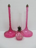 Two Cranberry glass lamp bases and one oil lamp