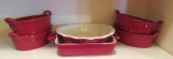Nine pieces of red oven proof ware, four oval casseroles, pie plate and square baker