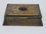 Ornate metal jewelry box with multi facet purple stone on top