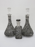 Three large cologne bottles with metal overlay