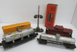 Four vintage Lionel train cars, one stock car box and signal