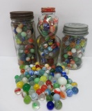 About 325 machine made marbles in three vintage jars