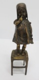 Bronze statue of girl on stool holding her shoe, 12