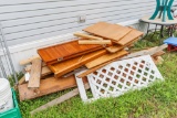 Large assortment of project lumber including 1 4x8 piece of osb inside building