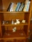 Items on 3 shelves: statues, candles, books, bells