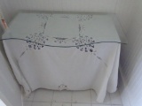 Wooden desk underneath glass top/tablecloth plus picture