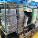 contents of shelf- stainless pans, cheese cutters, deli trays, cutting boards