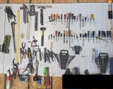 Mixed pegboard tools: hammers, pliers, cutters, snips, framing square, crowbar, end wrenches, screw