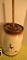 Butter churn top is a dark brown it has wooden paddle the body is cream color with 2 ducks with dark
