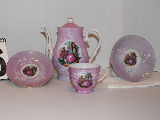pink porcelain tea pot with lid two pink porcelain saucers and a pink porcelain tea cup all have man