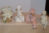 ceramic angels two are shelf sitting one white one orange in color a white angel sitting on a cloud