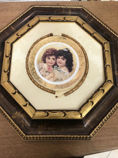 An Old ceramic plate with an image of two beautiful girls, plate is mounted in the heavyset intricat