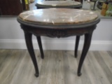 Oval side table with marble top and wooden legs.