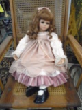Vintage doll, brown curly hair with a pinkish dress.