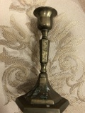 An old solid brass candle holder has a very delicate forms and flourish engravings on the brass surf