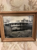 An old photo in the wooden frame. Two people standing on the bridge and overlooking the calmness of