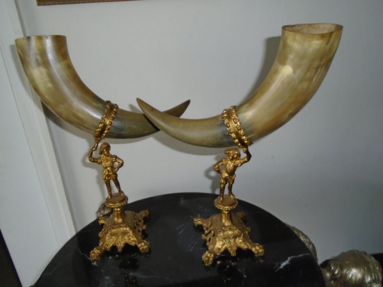 Pair of decorative gold metal figures holding horns.
