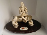 Carved and etched hippo ivory Sculpture of a man sitting holding tools and a child holding food.