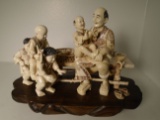 Carved and etched hippo ivory Sculpture of a man sitting on a bench with 4 playful children.