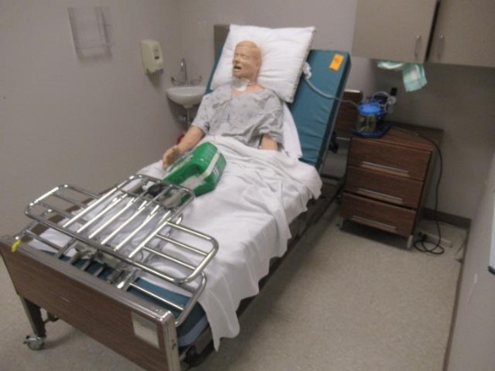 MEDICAL BED W/ TRAINING MANIKIN, ROLLING CABINET W/ PUMP & CONTENTS OF CABINET MOUNTED ON WALL