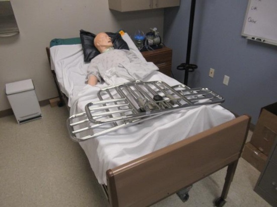 MEDICAL BED W/ TRAINING MANIKIN, ROLLING CABINET W/ PUMP & CONTENTS OF CABINET MOUNTED ON WALL