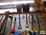 lot of hand tools on wall: rakes, shovels, pitchfork, etc.