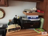 Lot of office supplies on counter, desk, and cupboard