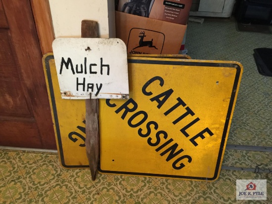 Two metal cattle crossing signs and mulch hay sign