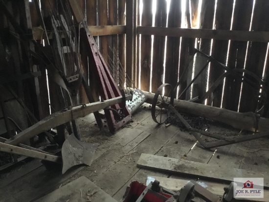 Antique farm equipment parts in corner: plow, frame, wheels, etc.
