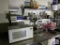 Contents of prep table: microwave, supplies, dishes, metal baskets, etc