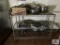 Metal rack with contents: cooking utensils, stainless steel bowls, skillets, etc