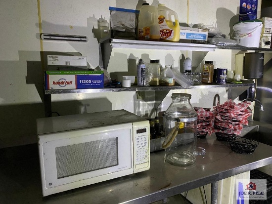 Contents of prep table: microwave, supplies, dishes, metal baskets, etc