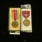 (2) Military Medals, one still in box (Crossed Swords & torch) with bar, other states 