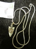Metal Arrowhead Pendant with an Indian Head cent design in the central area, mounted on a chain.