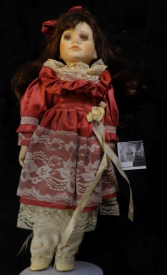 Female Doll on stand in a lace costume with bow in her hair. 15" tall.