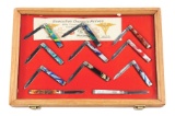 LOT OF 11: CASE FOLDING DOCTOR'S KNIVES COMPLETE WITH WOOD AND GLASS LOCKING DISPLAY CASE.