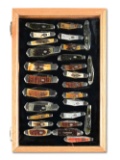 LOT OF 27: CRIPPLE CREEK FOLDING KNIVES IN WOOD AND GLASS LOCKING DISPLAY.