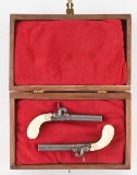 (A) CASED SET OF ENGRAVED BELGIAN IVORY HANDLE MUFF PISTOLS.