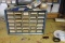 Organizer with misc. machine screws and several drawers empty. Buyer to remove from wall.