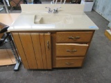BATHROOM SINK WITH FIXTURE AND CABINET. DRAWER NEEDS REPAIRED.