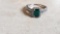 925 ring with green rectangle gemstone surrounded with clear gemstones and two rows of gemstones on