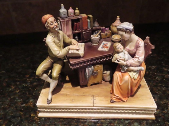 A. Borsato, Milano, made in Italy, woman and man at table with child figurine. The man's finger is