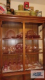 Lot of assorted pink glassware inside cabinet including some depression glass