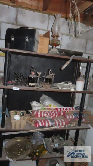 Contents of shelving including metal lamp holders, vintage bottles, oil lamp, lunch box, flags fan,